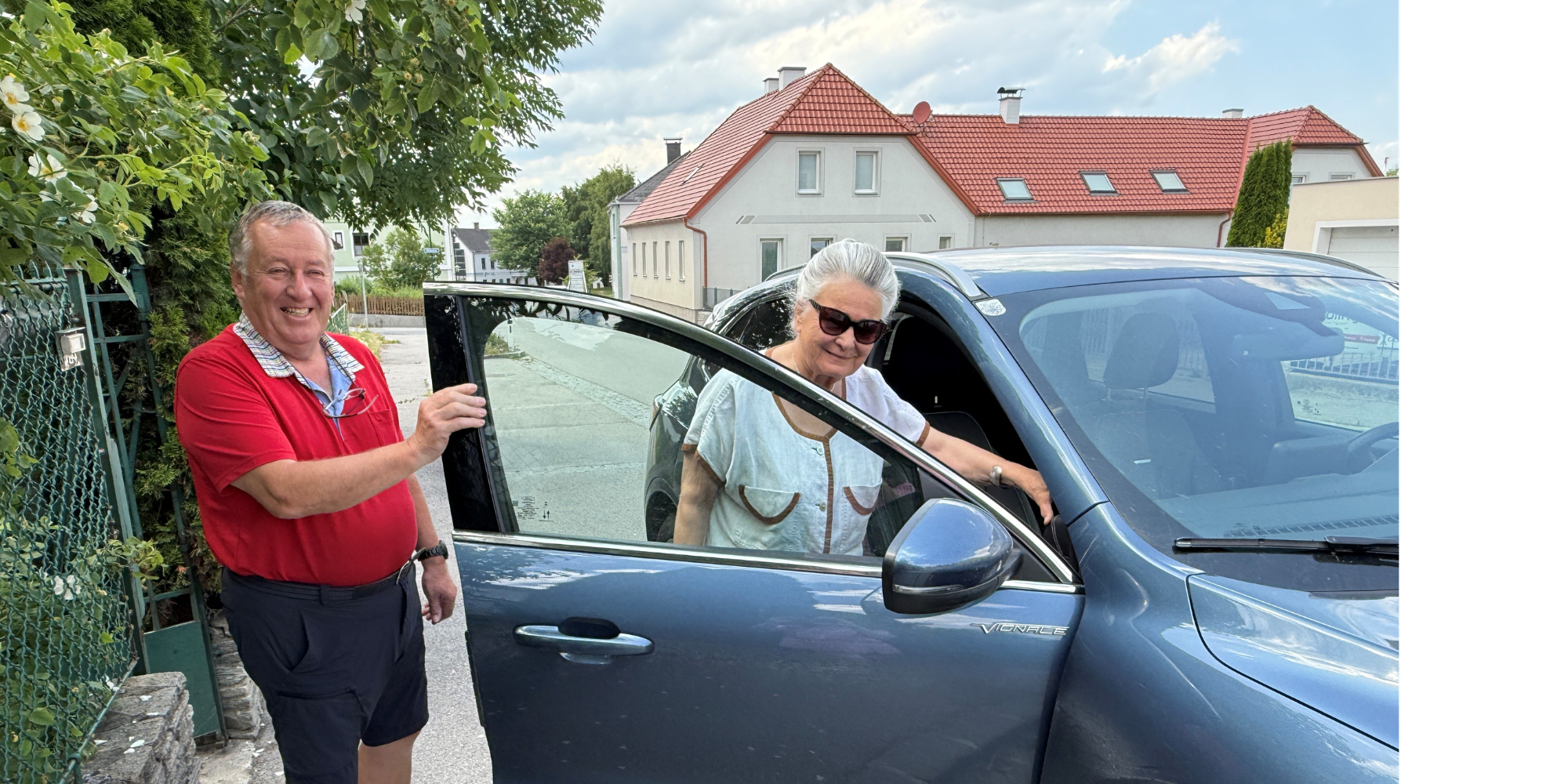Foto von einer Frau der von einem Mann die Tür eines Autos aufgehalten wird.
