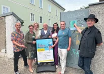 Eine Gruppe von Personen steht vor dem Plakat des Hitzeaktionstags.