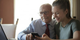 positiver-alterer-mann-und-lachelnde-junge-frau-die-smartphone-beim-sitzen-am-tisch-beobachten