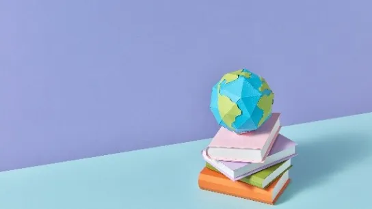 © Yaroslav Danylchenko/Stocksy - stock.adobe.com Ein kleiner Globus auf einem Bücherstapel